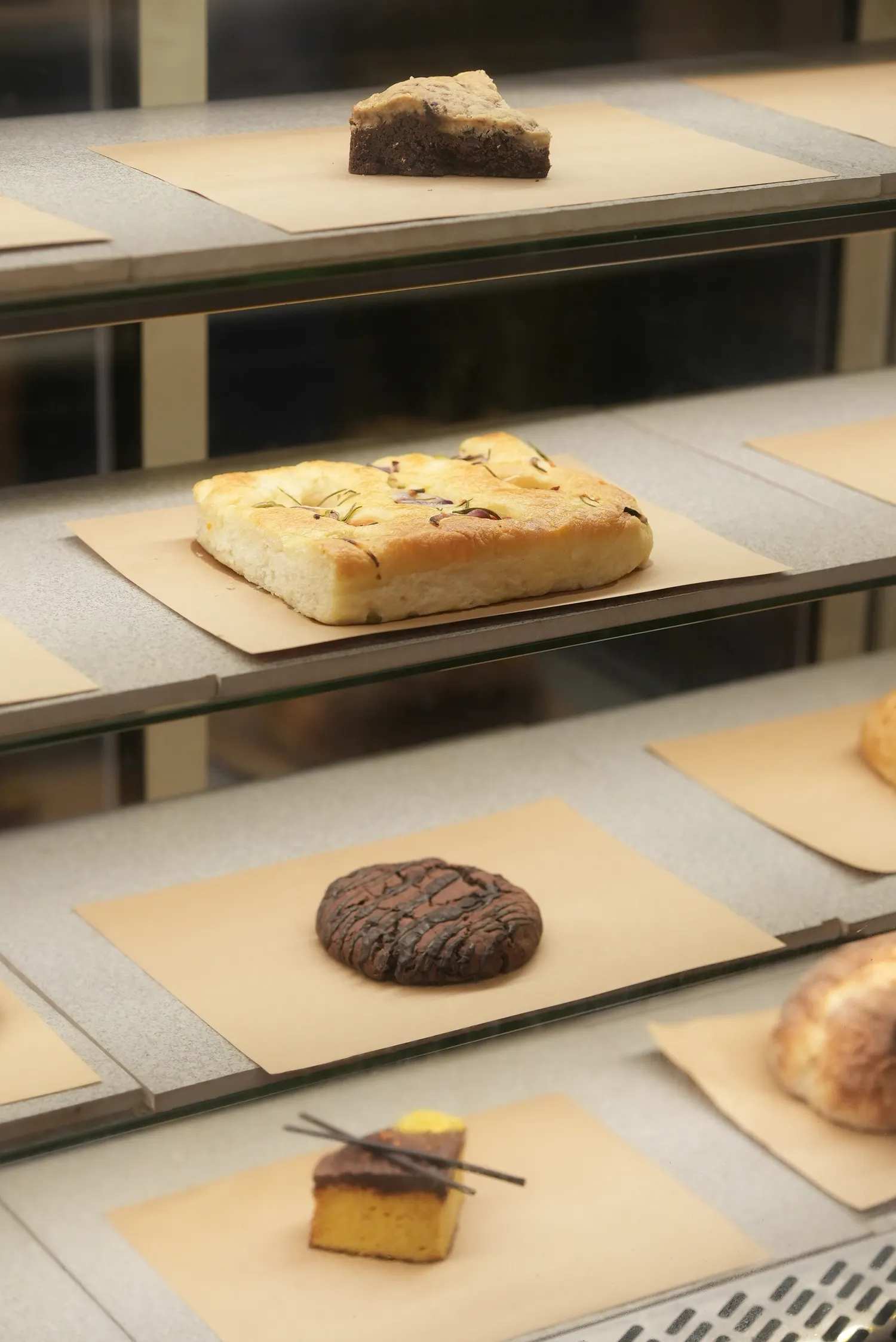 Focaccia, biscuits and cakes on the shelves of a bakery display case